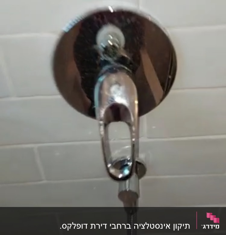 ברז מקלחת עם צינור מתכת על קיר אריחים
